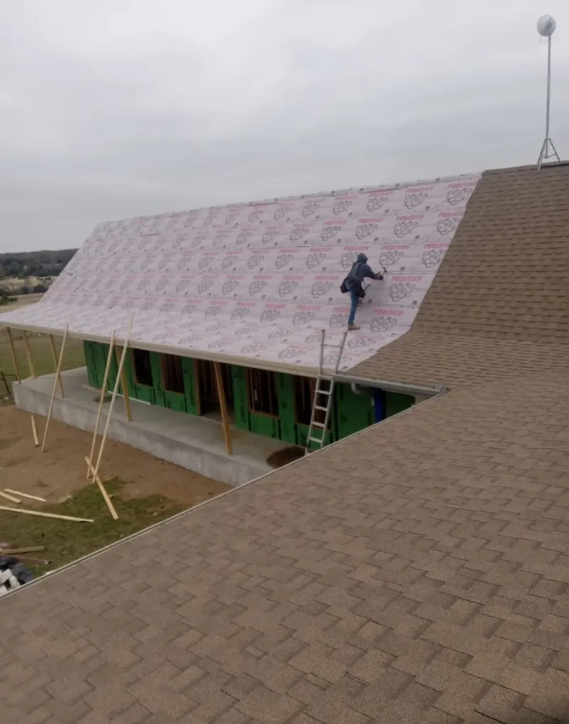 Worker preparing underlayment for a metal roof installation in Dumas